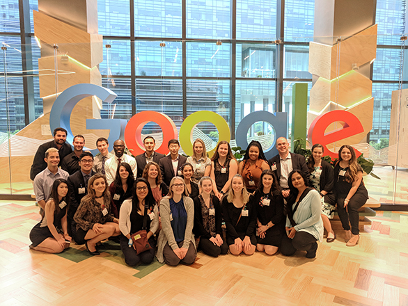 A group of student gather for a photo in front of the Google logo statue during a trip abroad.