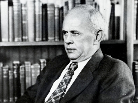Image of Rueben Thompson wearing a suit and tie, sitting in office in front of a bookshelf.