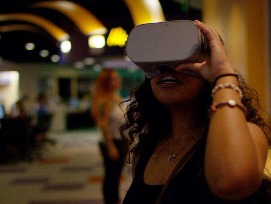 A female student wears a VR headset in the @One on the first floor of the Mathewson-IGT Knowledge Center