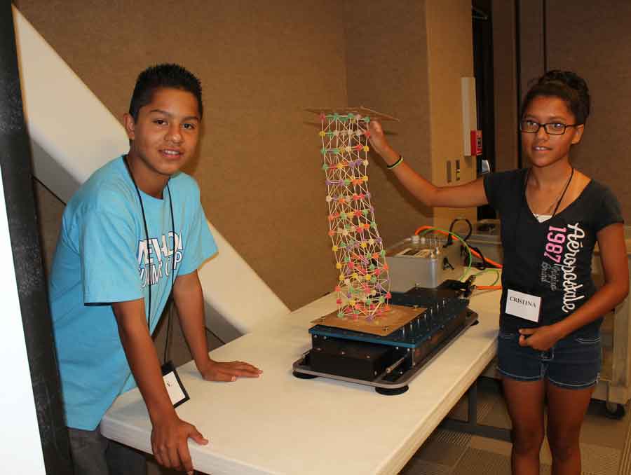 Two children standing near a table, which has a tower made of gumdrops on it.