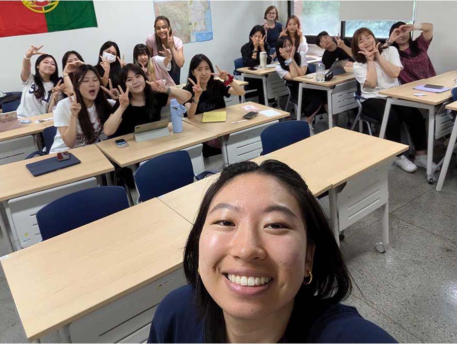 "Selfie" shot with Chanel Koh in foreground and students behind her in the background, shot in a classroom.